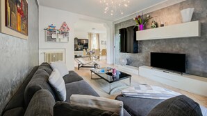 Ein modernes Wohnzimmer mit Sofa, Couchtisch, Fernseher und Dekorationselementen.