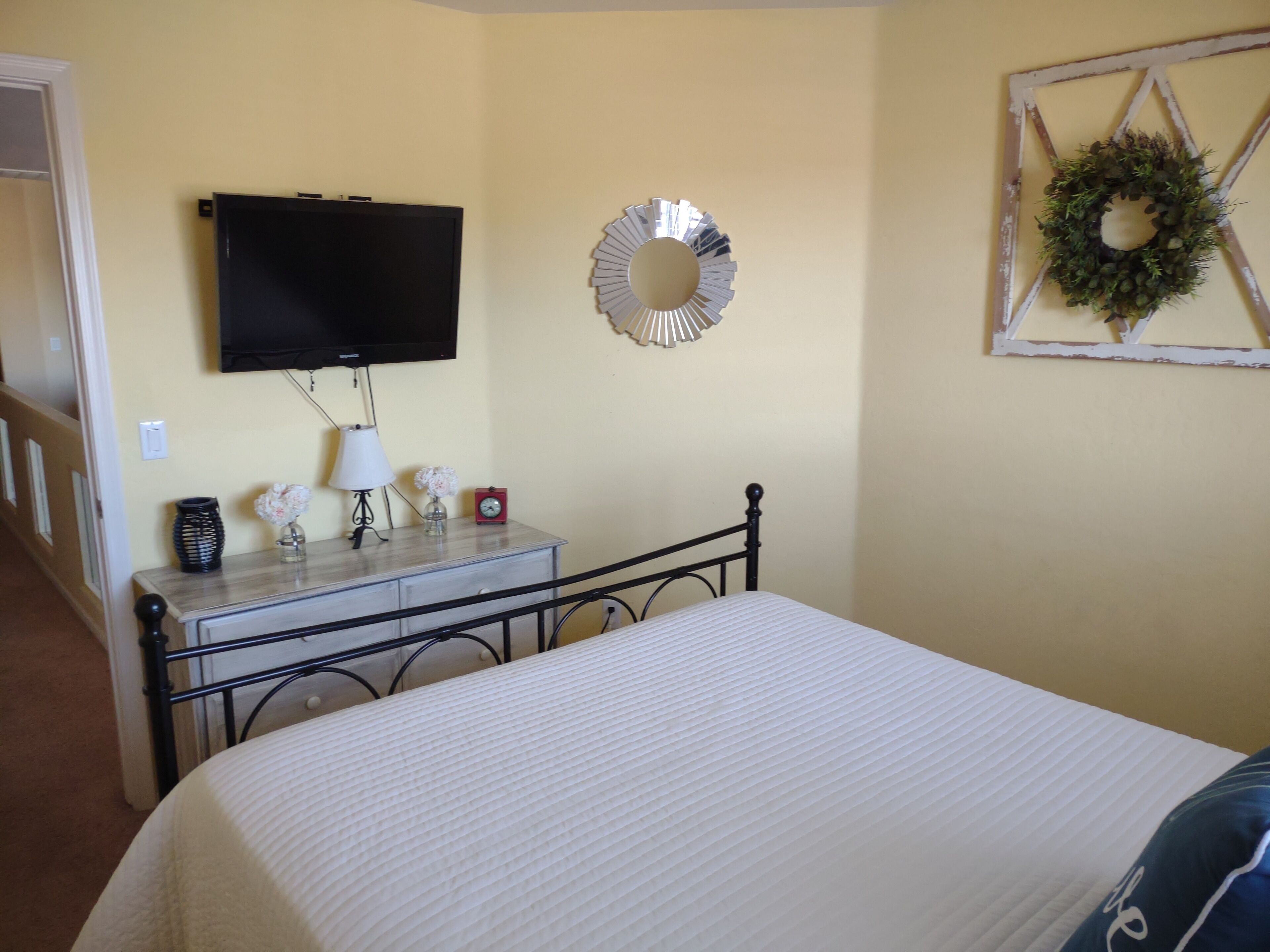 A bedroom with a bed, a dresser, a television, a clock, and wall decorations.