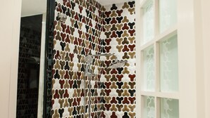 A bathroom with a patterned shower wall, a white sink, and a mirror. - Ai Luo Si (Guangzhou)