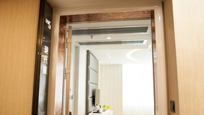 A hotel room with a modern design, including a large bed, a bedside table, and a television. - Ai Luo Si (Guangzhou)