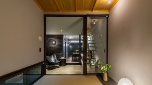 Un intérieur moderne avec une porte vitrée donnant sur un espace repas, un plafond en bois et une petite table entourée de chaises.
