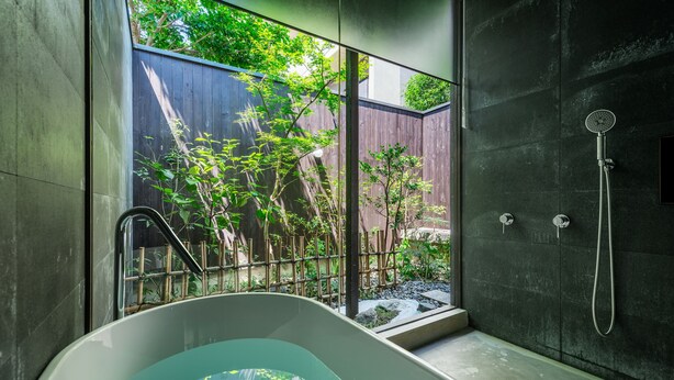 Une salle de bain moderne avec une baignoire sur pieds, une douche en verre et une vue sur un jardin grâce à une grande fenêtre.