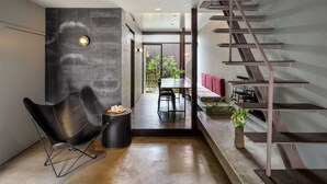 Un intérieur moderne avec une chaise noire, un coin repas et un escalier.