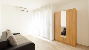 A modern room with a sofa, a wooden wardrobe, and a window with curtains.