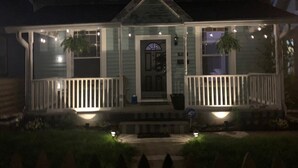 Une maison avec un porche, une porte d’entrée et un petit jardin.