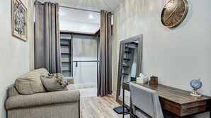 Un salon moderne avec un canapé, une table à manger, un miroir et une horloge.