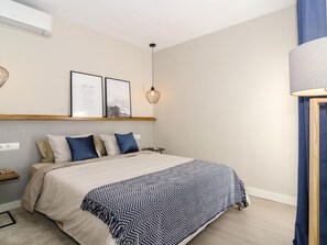 Un dormitorio con cama, mesita de noche, estante en la pared y lámpara colgante.