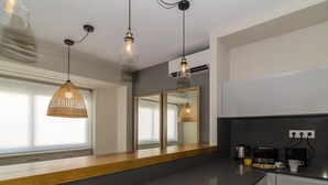 Cozinha moderna com bancada escura, parapeito de janela de madeira e luminárias pendentes.