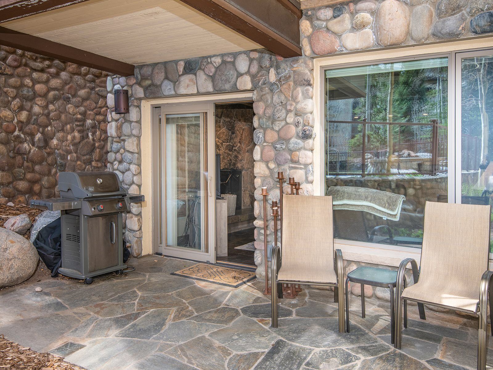 Un patio de piedra con una parrilla y mobiliario de exterior.
