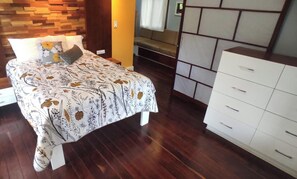 A bedroom with a bed, a white dresser, and a wooden headboard.