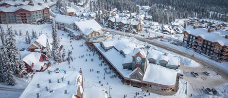 Estación de esquí nevada con varias cabañas y un telesilla.