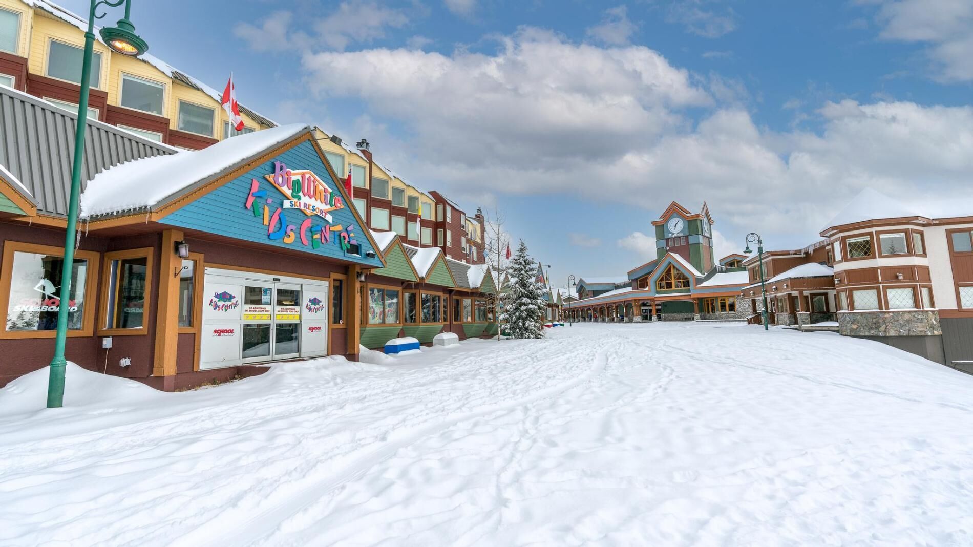 A snow-covered street with buildings, including a ski resort and a school.