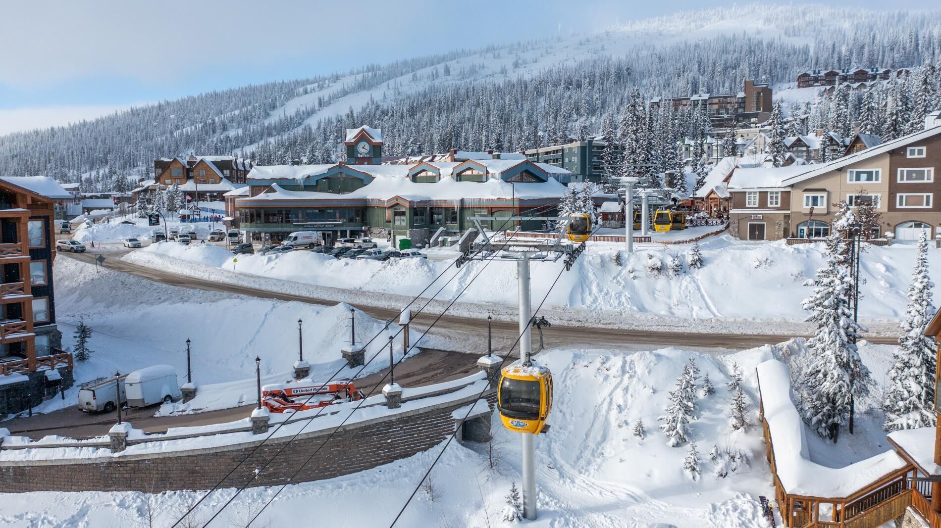 A snow-covered ski resort with buildings, a ski lift, and a road.