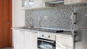 Una cocina moderna con armarios de madera clara, salpicadero de azulejos, electrodomésticos de acero inoxidable y un horno doble.