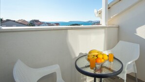 Un balcón con mesa y sillas, un cuenco de fruta y un vaso de jugo de naranja.