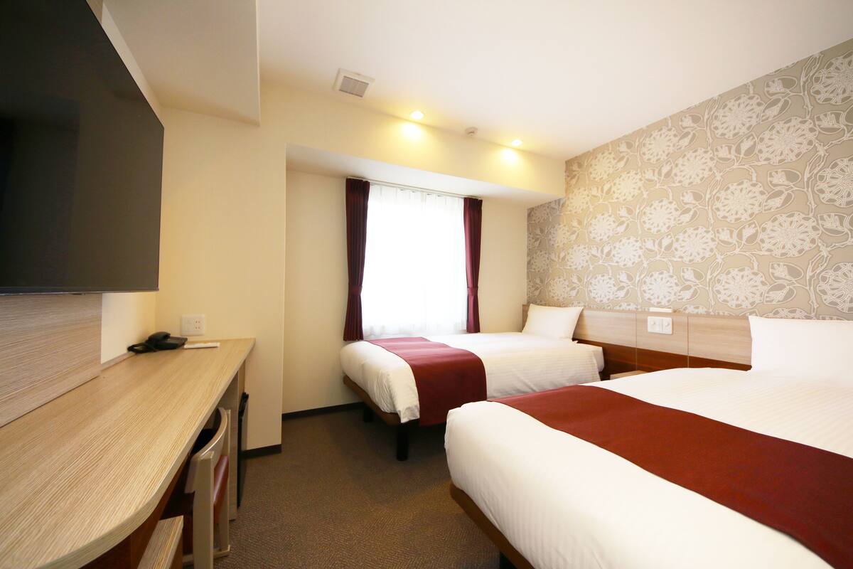 A hotel room with a bed, a desk, and a television.