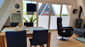 Ein moderner Wohnraum mit Essbereich, einem schwarzen Stuhl, einer Couch und einem Kamin.