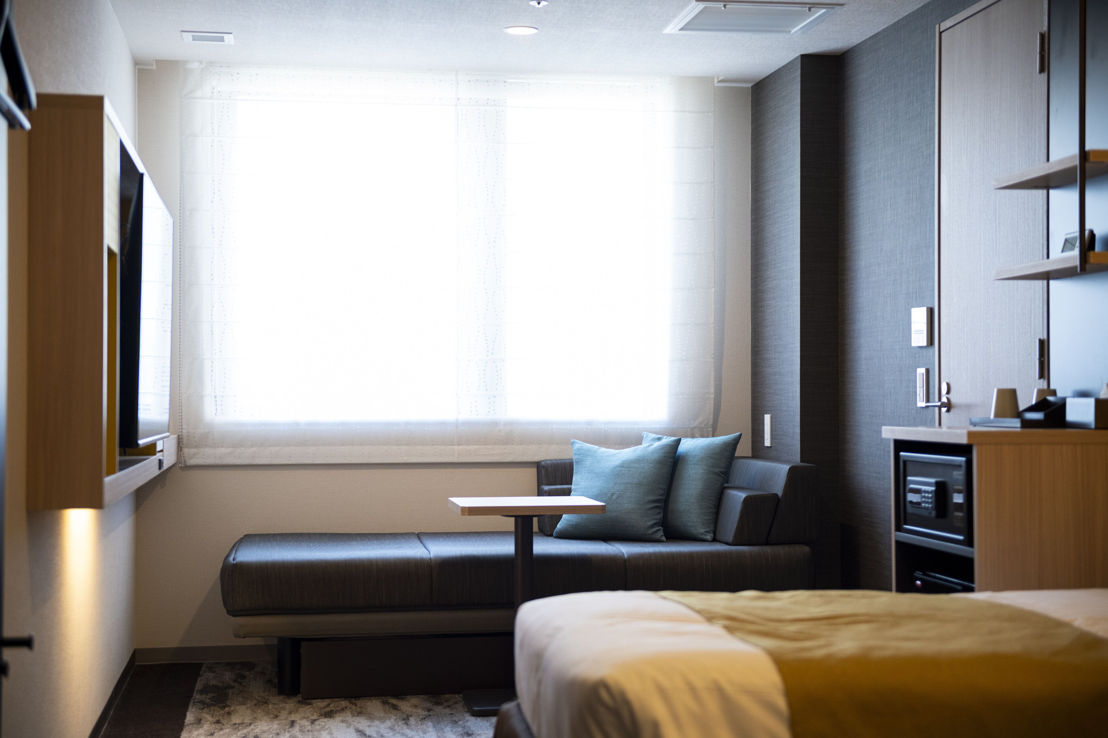 A modern hotel room with a large bed, a seating area with a table, and a television.
