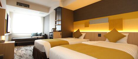 Habitación de hotel con dos camas, un sofá, un escritorio y un ventanal grande.