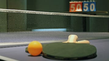A table tennis table with a net, a ball, and a paddle.