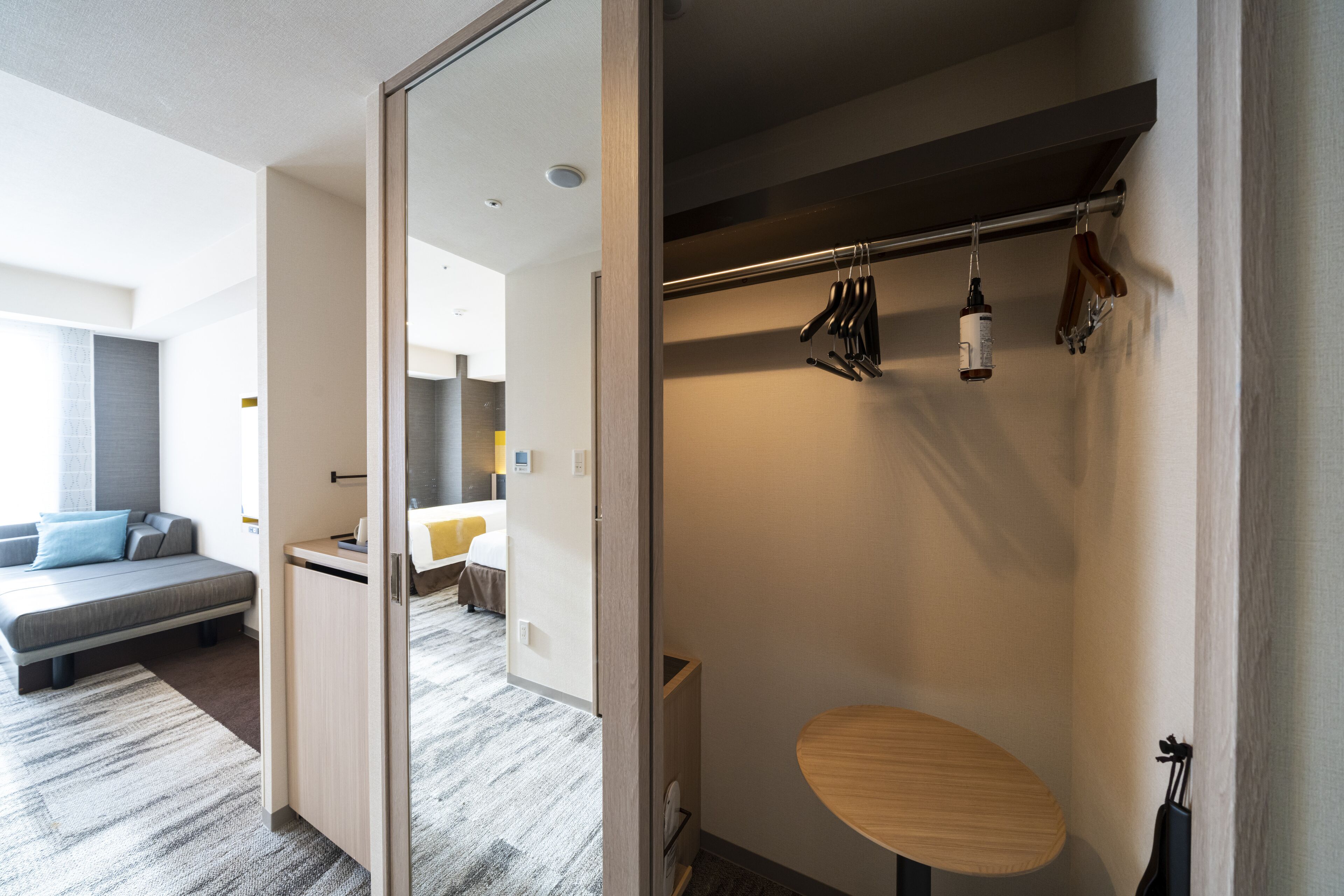 A modern hotel room with a bed, a small round table, and a shower area.