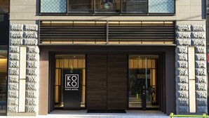 Een moderne hotelentree met een opvallend logo, grote glazen deuren en een goed verlichte gevel.