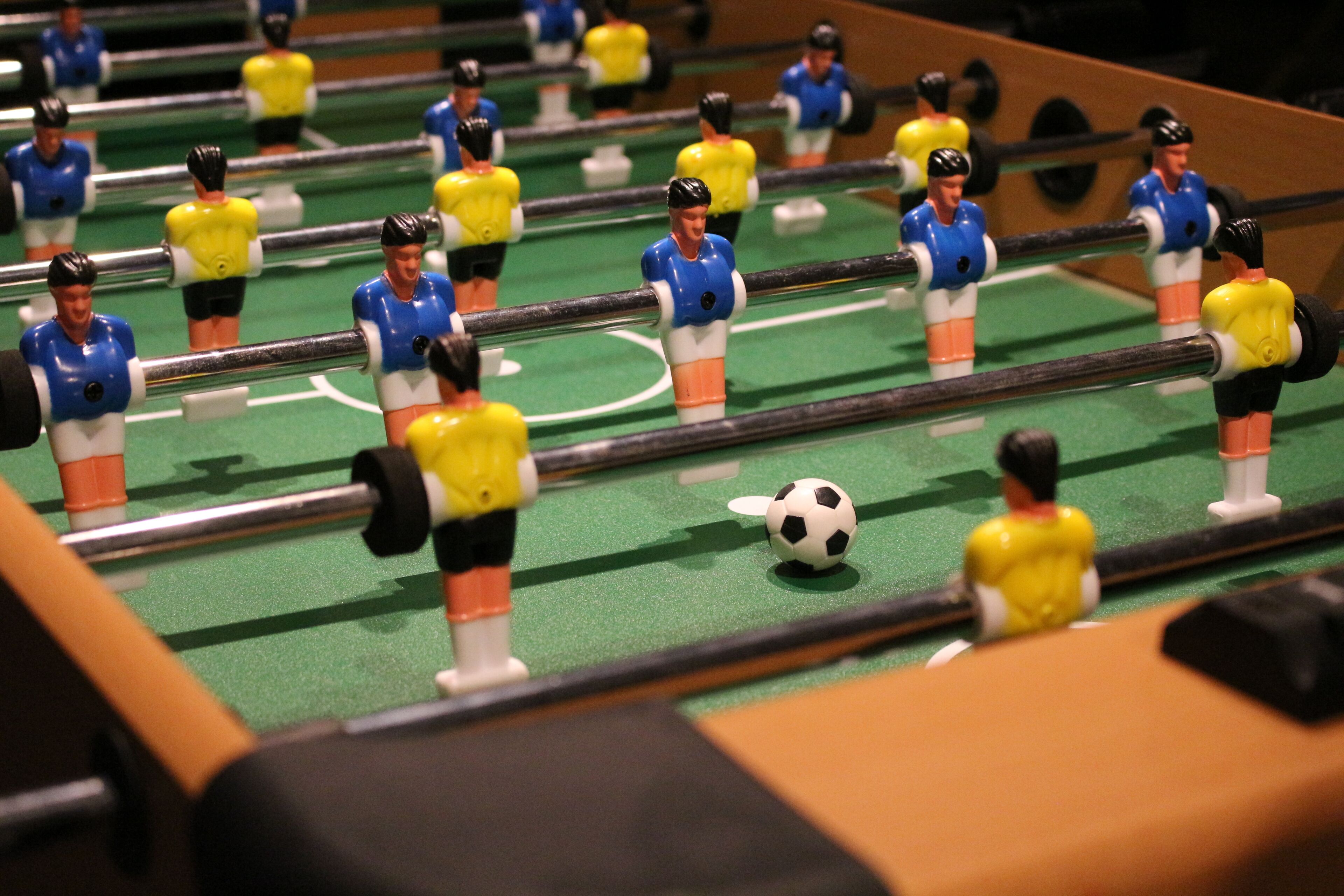 A foosball table with players in blue and yellow uniforms.
