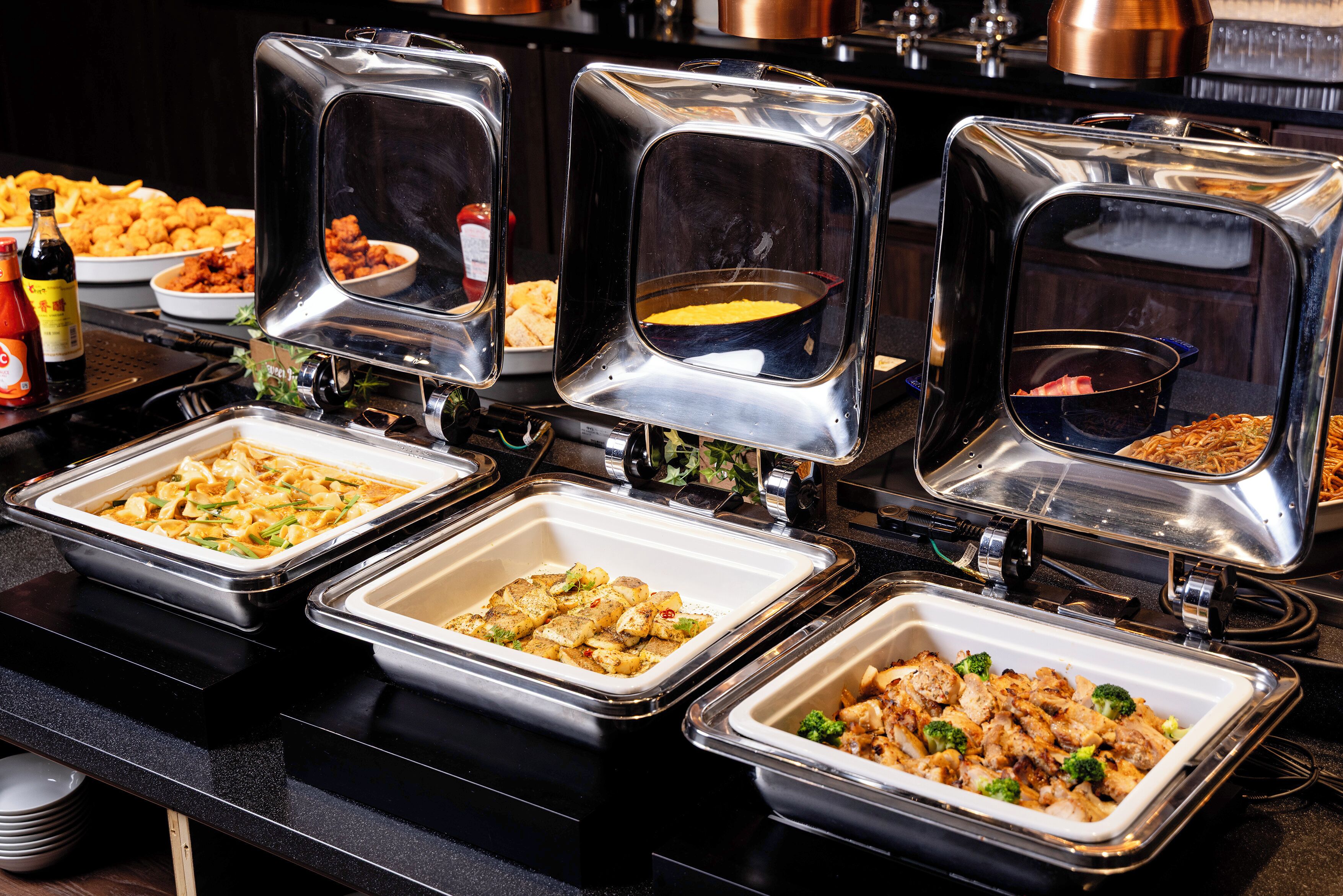 A buffet with various food items in metal serving trays.