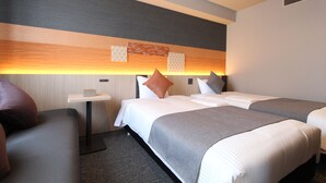 Een hotelkamer met twee bedden, een tafeltje en een bank.