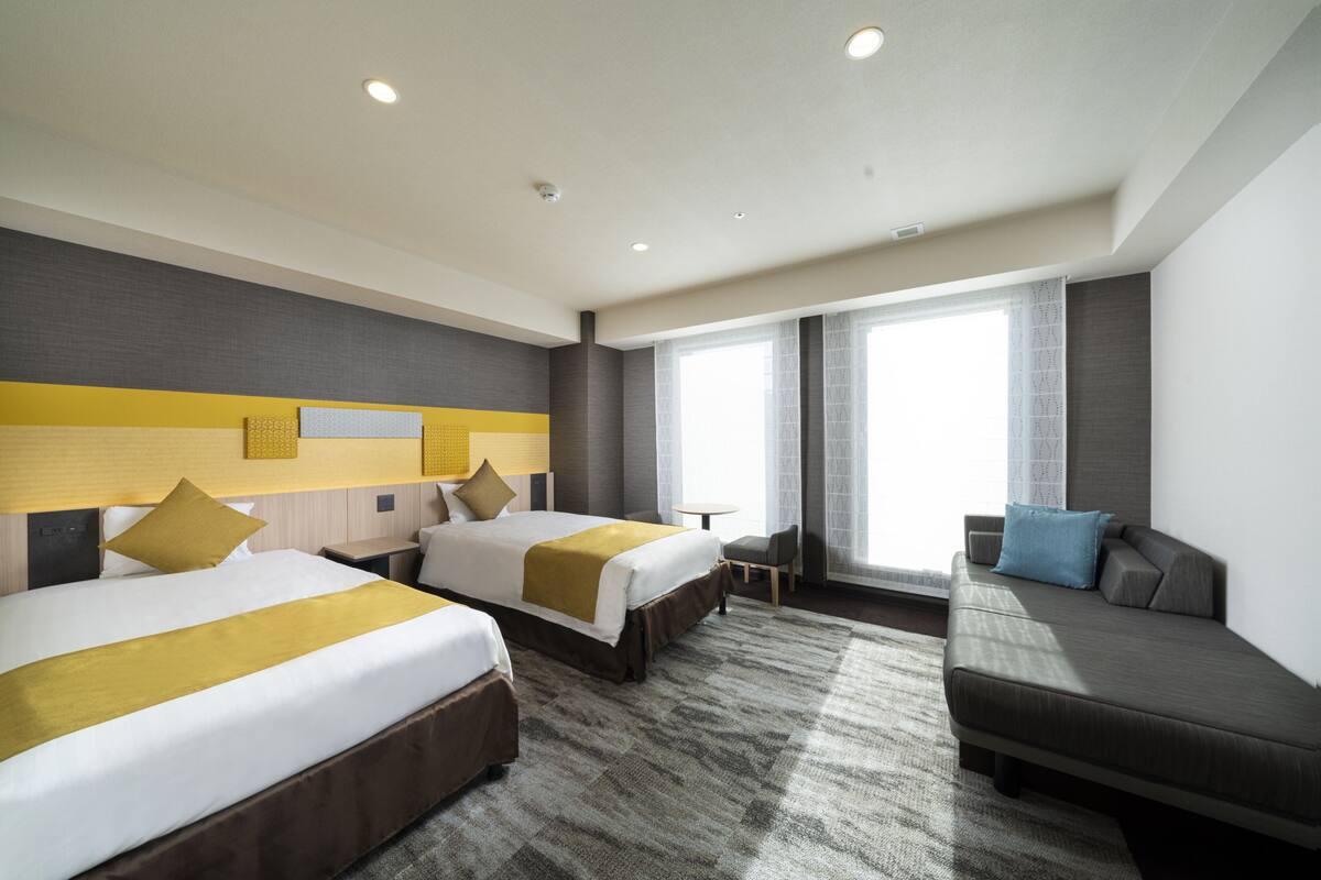 Une chambre d’hôtel avec deux lits, un canapé et une petite table.