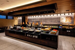 Zona de bufé con diferentes alimentos y un cartel grande que anuncia el hotel.