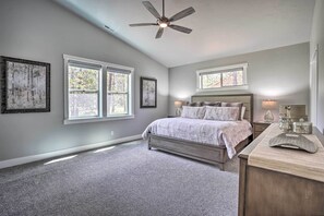 Quarto com cama, ventoinha no teto e grandes janelas.