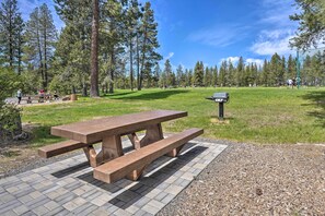 Uma mesa de piquenique num parque, com céu limpo e árvores ao fundo.