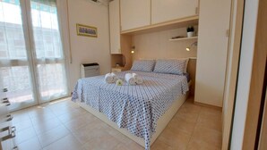Une chambre à coucher avec un lit, un bureau, une chaise, une petite table et une plante en pot.