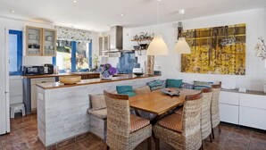 A modern kitchen with a central island, dining area, and a large abstract painting on the wall.