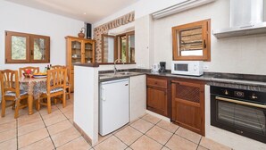 A compact kitchen with a refrigerator, microwave, stove, and a dining area with a table and chairs.