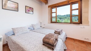 Ein Schlafzimmer mit zwei Betten, einem Fenster mit Blick und einer Holzbalkendecke.