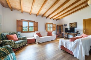A spacious living room with wooden flooring, a high ceiling with exposed beams, and a television on a wooden table. - Villa Can Baixo with Sea Views, Wi-Fi, Garden & Shared Pool (Puerto de Sóller)