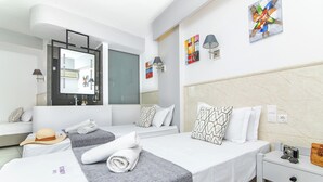 A modern hotel room with two beds, a large mirror, artwork on the walls, and a small table with a camera and a handbag. - Icandy Malia (Hersonissos)