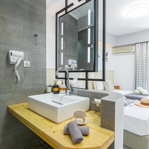 A modern bathroom with a large mirror, a white sink, and a hairdryer on the wall. - Icandy Malia (Hersonissos)
