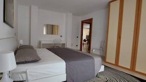 Een hotelkamer met een bed, nachtkastje, lamp en spiegel.