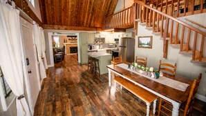 Eine geräumige Küche mit Holzböden, ein Essbereich mit einem Holztisch und Stühlen sowie eine Treppe mit hölzernen Geländern.