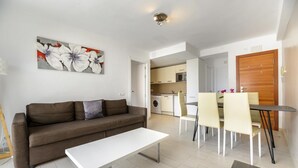 Een moderne woonkamer met een bank, een witte salontafel en een eethoek met stoelen en een tafel.