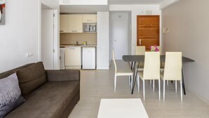 Een modern appartement met een zithoek, eetgedeelte, keuken en een houten deur.