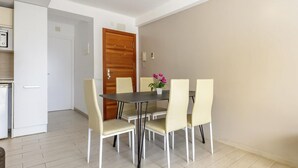 Een eethoek met een tafel en stoelen, een houten deur en een keuken met een koelkast.
