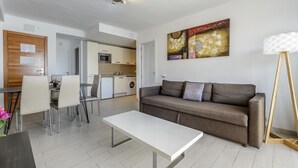 A modern living room with a sofa, a coffee table, and a dining area with chairs.