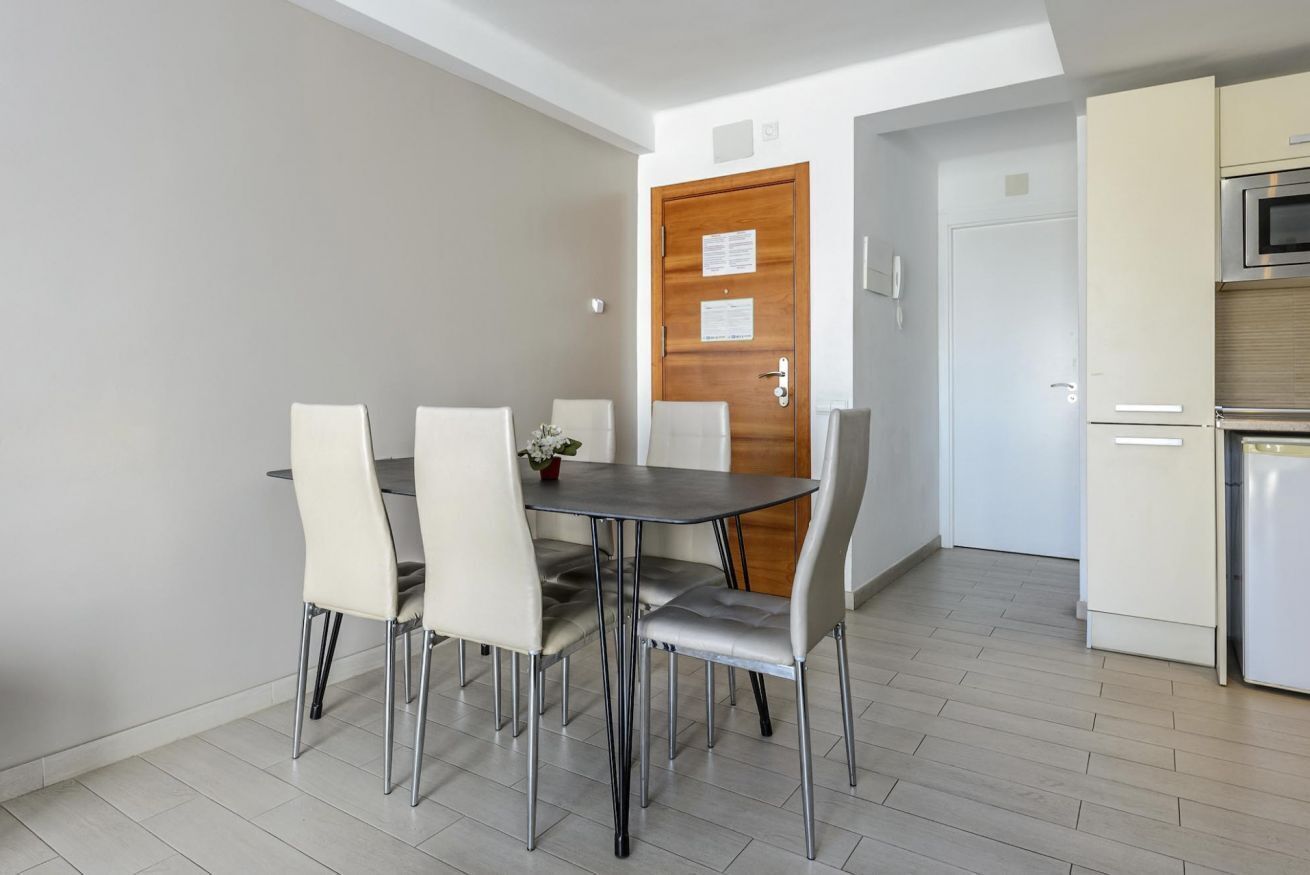 A dining area with a table and chairs, a wooden door, and a kitchen with appliances.