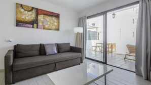 A modern living room with a grey sofa, a white coffee table, and a large abstract painting on the wall.