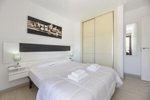 Une chambre d’hôtel avec un grand lit, une table de chevet avec une lampe, un tableau au mur et une porte coulissante.