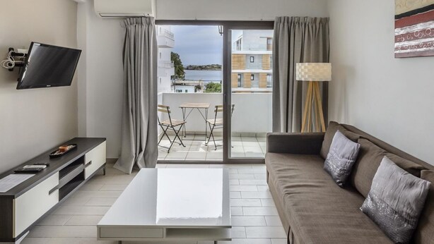 A modern living room with a sofa, a flat-screen TV, a coffee table, and a balcony with a view of buildings and a body of water. - Esmeralda apartment in Ibiza!!! 201 (Ibiza / Eivissa)